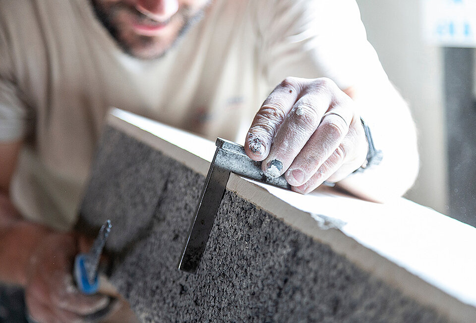 Ein Handwerker misst mit einem Anschlagwinkel die Kante eines Bauelements nach. Symbolbild für DIN-Normen und anerkannte Regeln der Technik nach der Rechtsprechung des BGH.